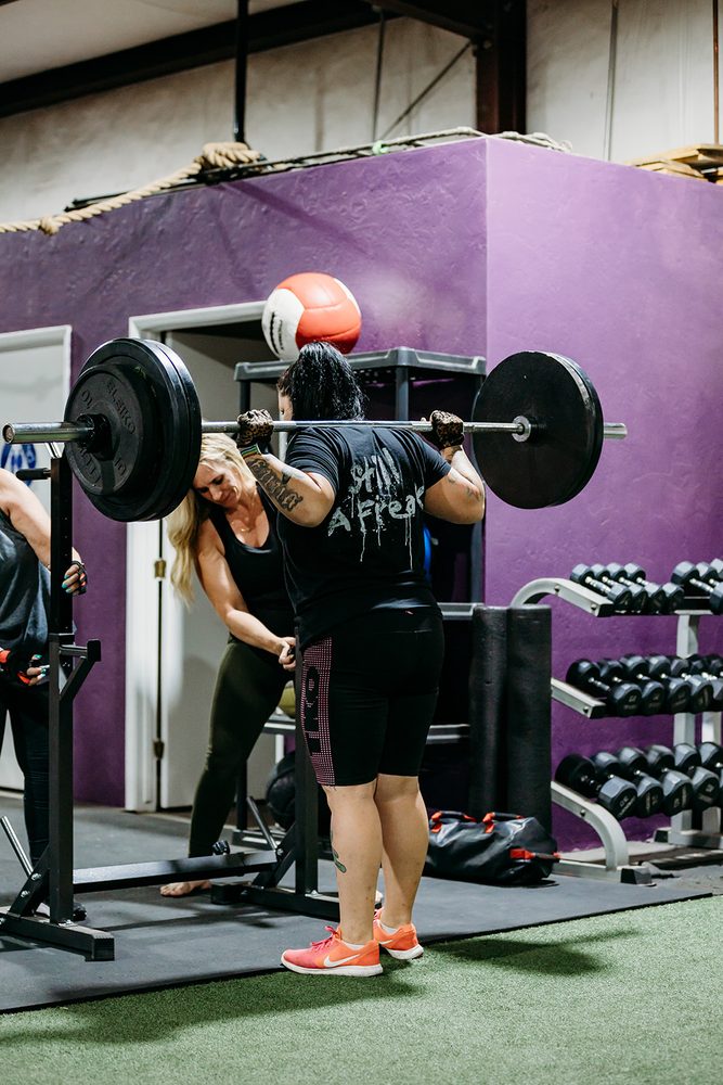A member performing a barbell clean at Train Like a Girl Studio