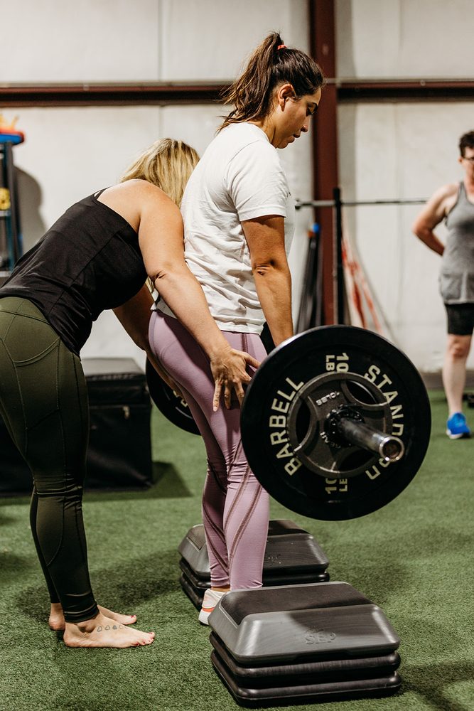 A coach guiding a member through a bent-over row