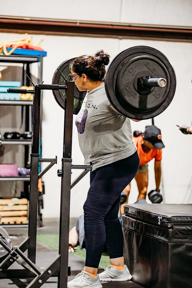 A member performing a back squat with a spotter