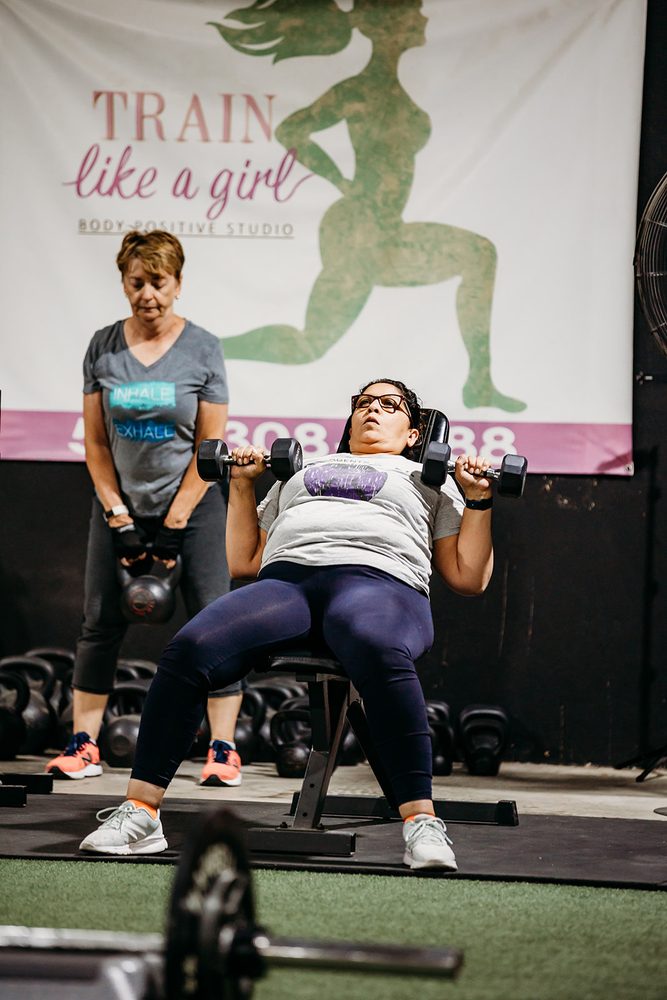 Strength training beneath the Train Like a Girl wall logo