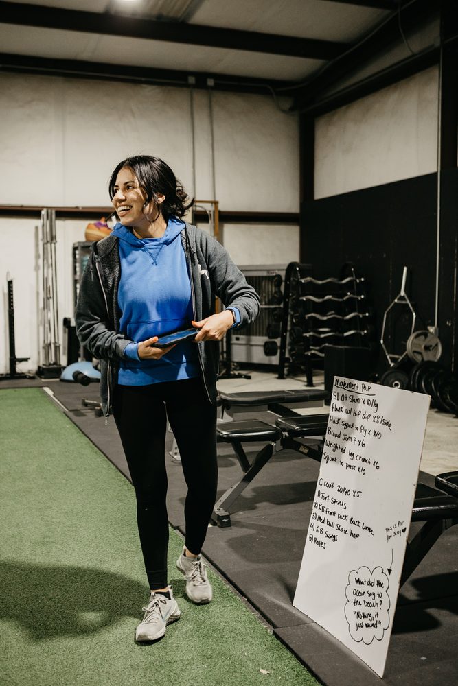 A coach leading class with the day's workout board